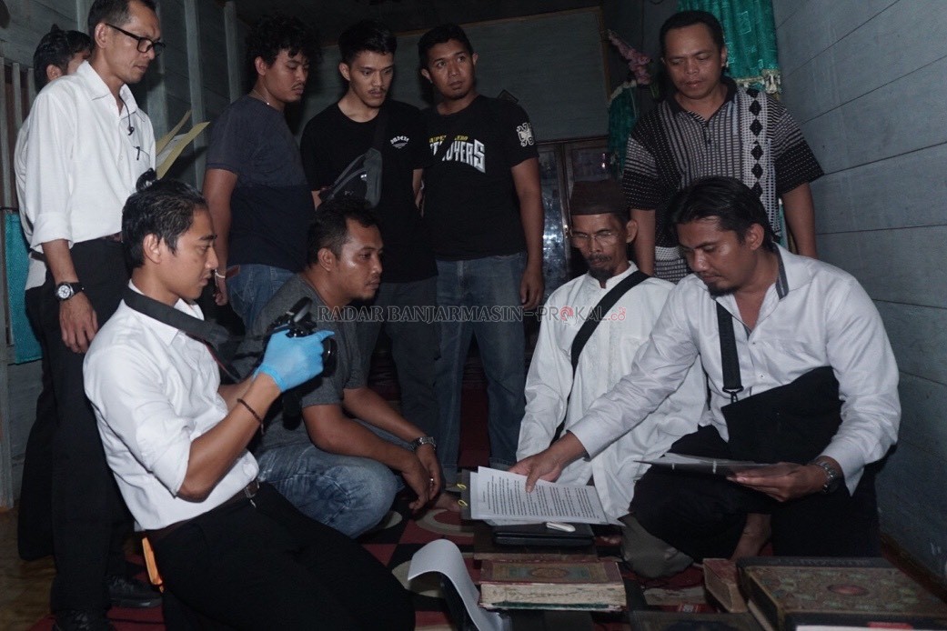 PASRAH: Nasruddin (berpeci), ketika menyaksikan proses penggeledahan di kediamannya beberapa waktu lalu. | FOTO: WAHYU RAMADHAN/RADAR BANJARMASIN