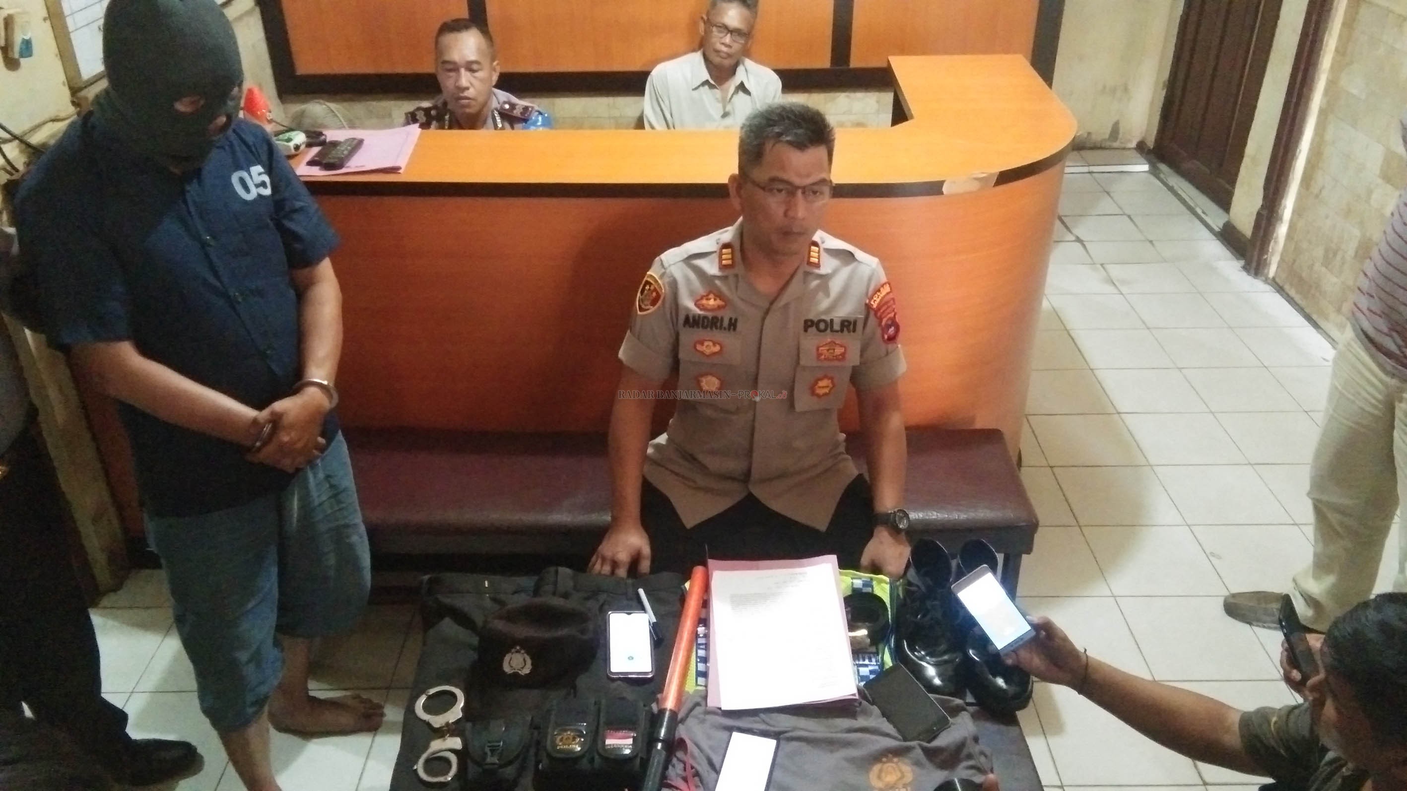 KAPOK: Kapolsek Banjarbaru Barat AKP Andri Hutagalung bersama pelaku penipuan, Budhi dan barang bukti seragam polisi saat jumpa pers di Mapolsek Banjarbaru Barat, kemarin. | FOTO: SUTRISNO/RADAR BANJARMASIN
