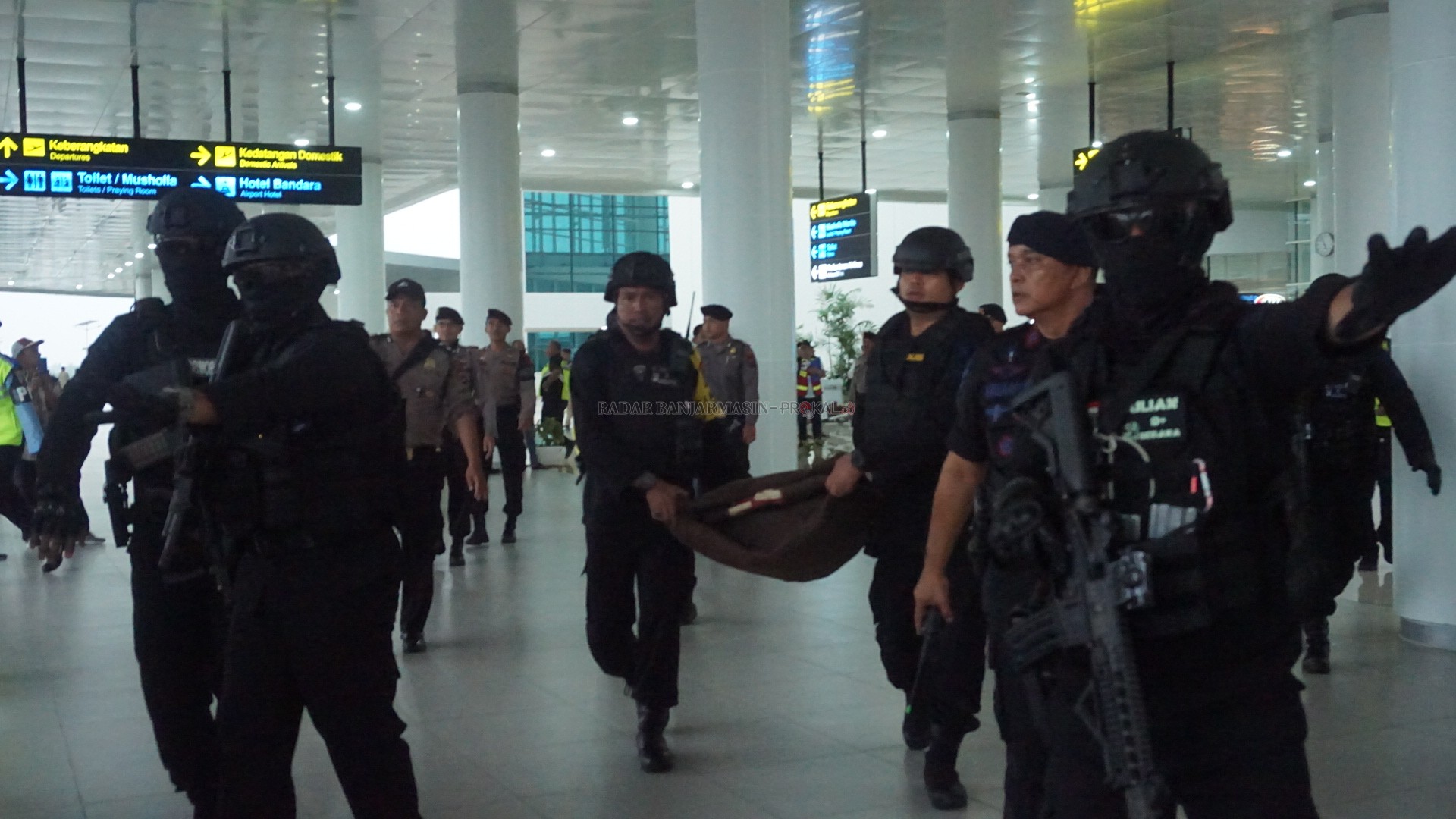 AMANKAN BANDARA: Tim Jipom Satuan Brimob Polda Kalsel membawa bungkusan barang yang diduga bom dalam simulasi Latihan Penanggulangan Keadaan Darurat (PKD) yang digelar di Bandara Internasional Syamsudin Noor, kemarin. | FOTO: SUTRISNO/RADAR BANJARMASIN