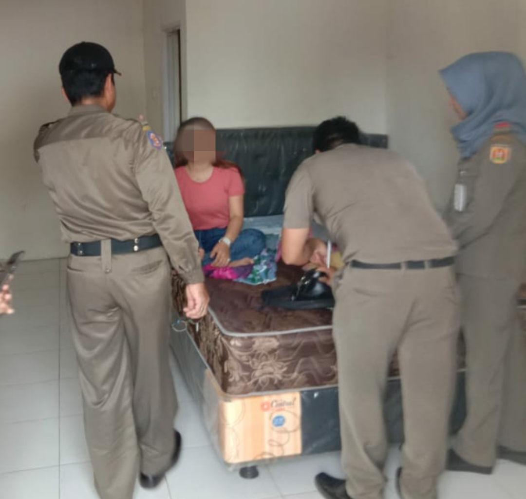 PASRAH: HL (duduk di kasur) tak dapat mengelak usai dirinya tepergok ngamar dengan teman kencan prianya di Penginapan Saudara Banjarbaru oleh Petugas Satpol PP Banjarbaru pada Selasa (12/2). | Foto: Satpol PP Banjarbaru for Radar Banjarmasin