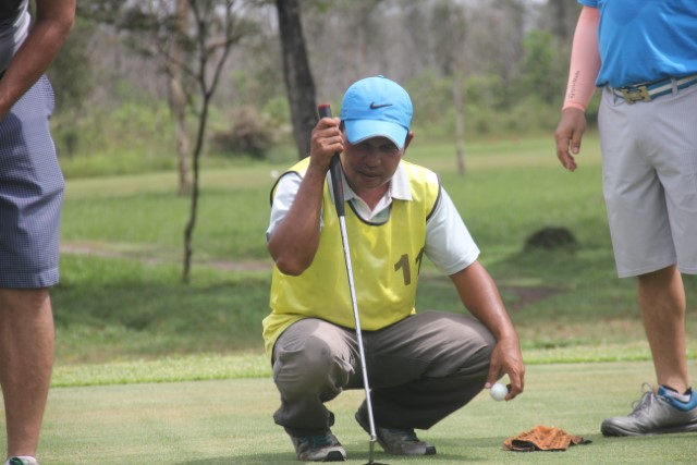 DUDUK: Ismail (kuning) ketika sedang menajdi caddy untuk Haji Juanda saat bermain di Padang Golf Swargaloka belum lama ini.