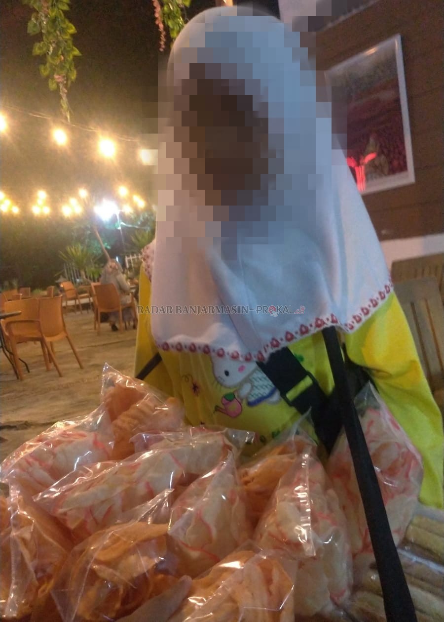 PANGGUL BEBAN: Putri -bukan nama sebenarnya- ketika tertangkap kamera berjualan kerupuk hingga larut malam di salah satu kedai kopi di pusat Kota Banjarbaru beberapa waktu lalu | Foto: Muhammad Rifani/Radar Banjarmasin