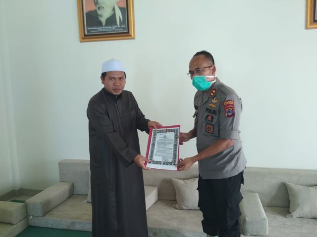 SERAHKAN MAKLUMAT: Kapolres Tanbu AKBP Sugianto Marweki menyerahkan maklumat Kapolri dalam pencegahan Covid-19 kepada Ketua MUI Tanbu KH Fadli Muis. (Foto Karyono/Radar Banjarmasin).