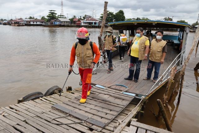 DISINFEKSI: Badan kapal sampai titian dermaga disemprot dengan cairan disinfektan, kemarin di Sungai Alalak. | FOTO: MUHAMMAD OSCAR FRABY/RADAR BANJARMASIN