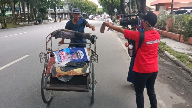 Belasan jurnalis membagikan masker kepada warga yang melintasi perempatan Jalan Lambung Mangkurat, kemarin (13/4) siang.