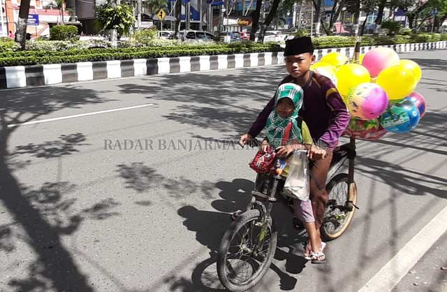 HARUS DIBANTU: Bocah berdagang balon melintasi Jalan Lambung Mangkurat, kemarin (13/4). Warga kecil inilah yang harus ditolong. | FOTO: WAHYU RAMADHAN/RADAR BANJARMASIN