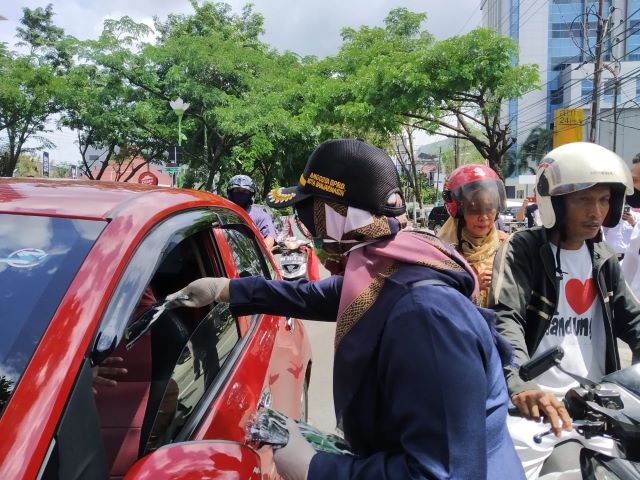 BAGI MASKER: Anggota Komisi IV DPRD Banjarmasin membagikan masker kepada pengendara yang melintasi Jalan Lambung Mangkurat, kemarin. | FOTO: FAHRIADI NUR/RADAR BANJARMASIN