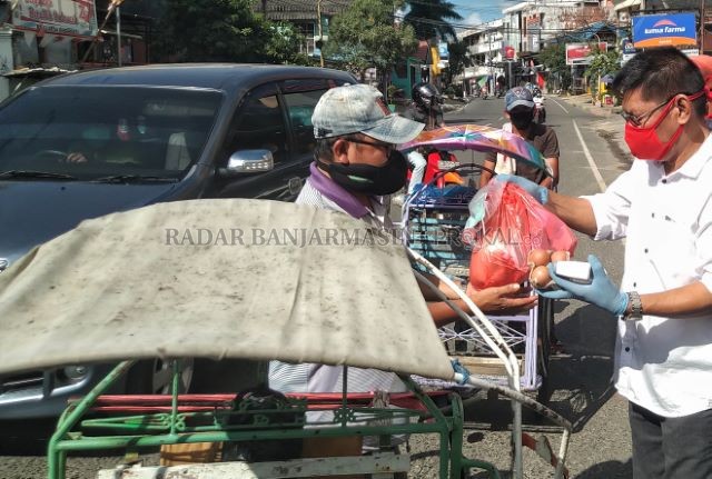 RAWAN TERTULAR: Zulkifl i, salah seorang pimpinan parpol di Kotabaru membagikan masker kepada para pekerja di jalanan. Pulau di bagian tenggara Kalsel itu bersiap untuk pandemi setelah satu warganya terdeteksi terpapar corona Jumat tadi. | Foto: ZALYAN SH
