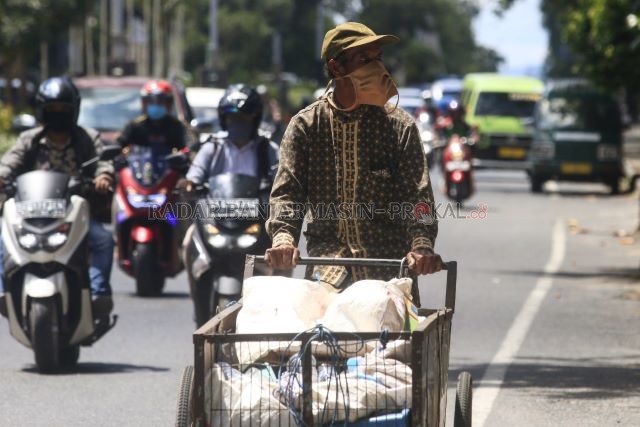 BAKAL TERDAMPAK PSBB: Seorang warga mengayuh gerobak berisi barang bekas di Jalan A Yani Kota Banjarbaru. Pemko memutuskan untuk mengusulkan PSBB ke pusat, menyusul peningkatan kasus pandemi Covid-19. Jika PSBB diterapkan, aktivitas warga termasuk bekerja