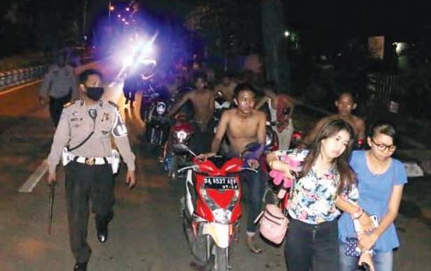 SANKSI KHUSUS: Puluhan remaja yang terjaring balapan liar di Lapangan Murjani pada Selasa (28/4) dini hari, disuruh mendorong motornya sambil menyanyikan lagu Ibu ketika menuju Mapolres Banjarbaru. | FOTO: POLRES BANJARBARU FOR RADAR BANJARMASIN