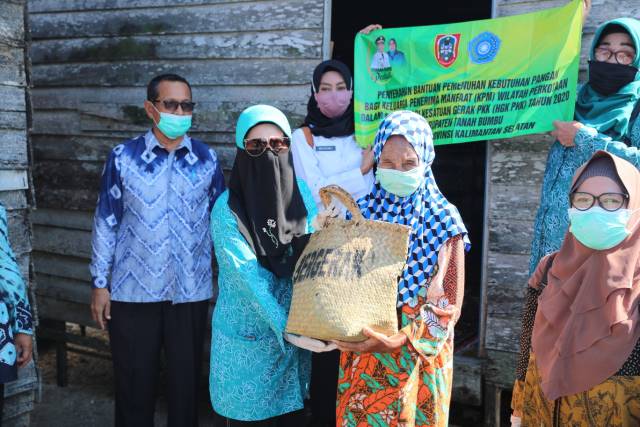SERAHKAN SEMBAKO: Hj Sadariah menyerahkan bantuan berupa sembako dari Dinas Sosial Kalsel kepada warga Kusan Hilir yang terdampak virus Covid-19. (Foto Diskominfo Tanbu For Radar Banjarmasin).