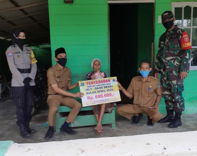 MENYERAHKAN: Camat Sungai Loban menyerahkan Bantuan Langsung Tunai (BLT) kepada masyarakat tidak mampu yang terdampak Covid-19 di wilayah Kecamatan Sungai Loban, Selasa (12/5). (Foto Diskominfo Tanbu For Radar Banjarmasin).