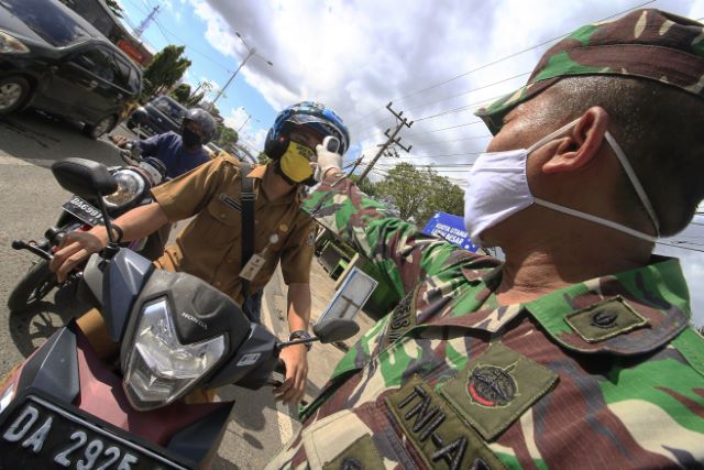 DI BAWAH TERIK: Salah satu petugas dari unsur TNI di posko 2 PSBB Gabungan di depan Q Mall Banjarbaru memeriksa suhu tubuh pengendara yang ingin masuk wilayah Banjarbaru. Beberapa warga terdeteksi punya suhu yang cukup tinggi, namun hal ini diakibatkan ol