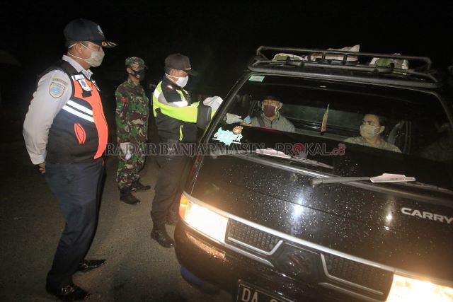 ARUS BALIK: Petugas gabungan di Posko 1 PSBB Kelurahan Bangkal Cempaka yang berbatasan langsung dengan Kabupaten Tanah Laut memeriksa surat pengantar dari pengendara yang lewat pada Rabu (27/5) malam. Setelah lebaran marak ditemukan warga yang terindikasi