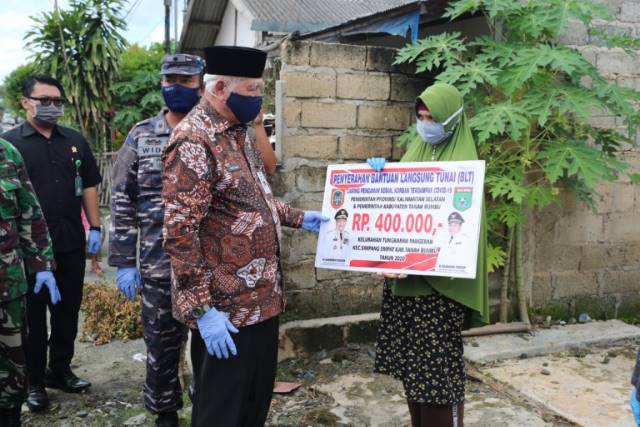 BANTUAN JPS: Wakil Bupati Tanah Bumbu H Ready Kambo menyerahkan dana bantuan jaring pengaman sosial (JPS) bagi warga yang terdampak Covid-19 secara simbolis kepada 10 orang warga Kelurahan Tungkaran Pangeran Kecamatan Simpang Empat, Kamis (4/6). (Foto Dis
