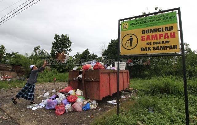 BERDAMPAK: Salah seorang warga melempar bungkusan sampah miliknya ke sebuah bak sampah di Jalan Trikora Banjarbaru. Selama pandemi, DLH Banjarbaru mencatat produksi sampah di Kota Banjarbaru menyusut hingga 20 ton perharinya. | FOTO: MUHAMMAD RIFANI/RADAR