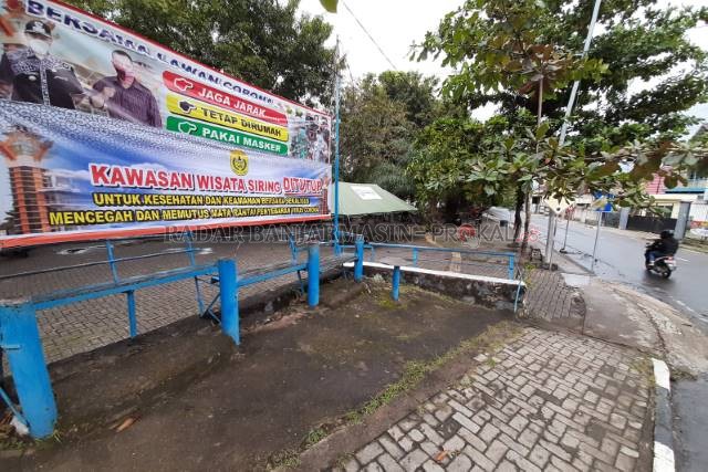 DITUTUP LAGI: Spanduk pemberitahuan penutupan Siring Pierre Tendean. Tampak di belakang ada posko untuk petugas pengawas. Warga Banjarmasin disarankan tidak mendatangi objek wisata itu pada akhir pekan ini. | FOTO: WAHYU RAMADHAN/RADAR BANJARMASIN