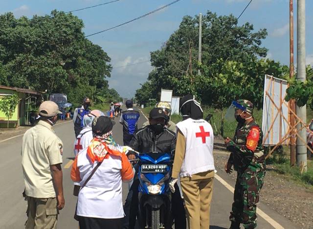 TEGAS: Petugas gabungan memeriksa pengendara yang lewat posko di perbatasan antara Kabupaten Tapin dan Barito Kuala. | Foto: Pusdalops for Radar Banjarmasin