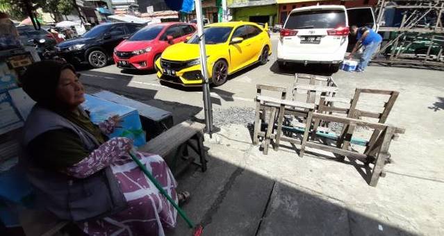 AYO BANTU: Yuliati tak mengenakan masker lantaran mengaku sulit bernafas. Selama menjaga parkir, mulut dan hidungnya hanya ditutupi dengan ujung kerudung. | Foto: Wahyu Ramadhan/Radar Banjarmasin