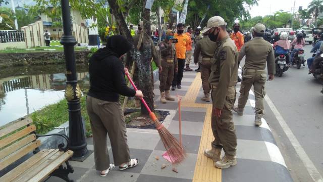 BIAR JERA: Seusai drama panas, warga Kuin Cerucuk ini akhirnya menyerah. Menerima sanksi sosial dengan menyapu trotoar Jalan Ahmad Yani. | FOTO: MAULANA/RADAR BANJARMASIN