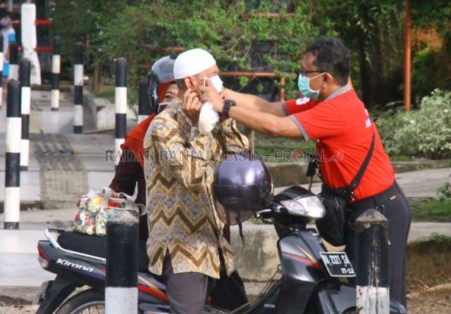 DIPASANGKAN: Petugas memasangkan masker kepada pengendara di Jalan Ahmad Yani  kilometer 6. Foto diambil selama penerapan PSBB  di Banjarmasin. | Foto: Maulana/Radar Banjarmasin