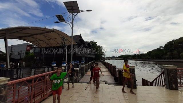BERMAIN TANPA MASKER: Anak-anak bermain di dekat Menara Pandang, Siring Pierre Tendean, seusai Banjarmasin diguyur hujan deras, kemarin (28/9) sore. | FOTO: WAHYU RAMADHAN/RADAR BANJARMASIN