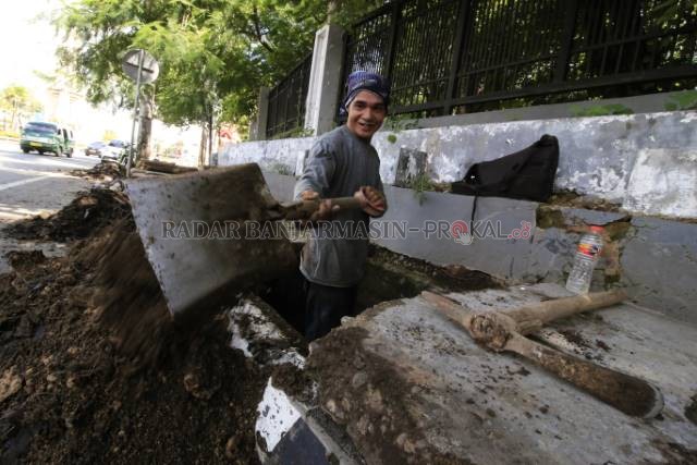 BAKAL BERGULIR: Salah seorang pekerja melakukan pekerjaan normalisasi saluran drainase di ruas jalan A Yani Banjarbaru beberapa waktu lalu. Bidang Bina Marga Dinas PUPR Banjarbaru akan mulai merealisasikan program padat karya pekan awal bulan Oktober ini.