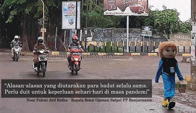 LANGKAH GONTAI: Seorang badut berjalan pelan di perempatan lampu merah Jalan Teluk Tiram Darat, kemarin (13/10) siang. | FOTO: WAHYU RAMDHAN/RADAR BANJARMASIN