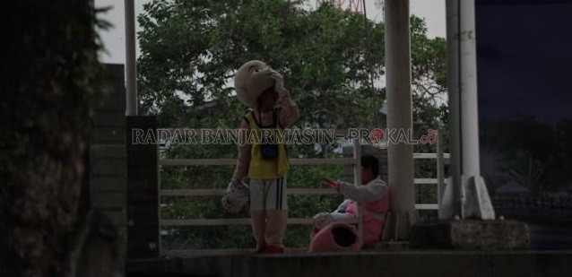 MELEPAS PENAT: Dua badut jalanan bersantai di Siring RE Martadinata, seberang kantor Wali Kota Banjarmasin, kemarin (14/10) sore. | Foto: WAHYU RAMADHAN/RADAR BANJARMASIN
