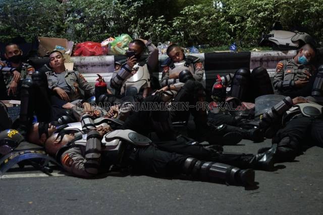 SAMA-SAMA LELAH: Demonstran bertahan sampai Kamis (15/10) tengah malam. Banyak mahasiswa yang tiduran di aspal. Sementara aparat yang mengamankan, bergantian istirahat. | FOTO: WAHYU RAMADHAN/RADAR BANJARMASIN