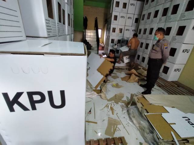 DIJAGA: Dikawal aparat kepolisian, sejumlah relawan mulai merakit kotak suara yang baru tiba di gudang logistik KPU Banjarmasin.