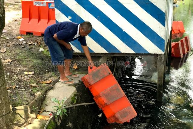 JADI REPOT: Warga Teluk Dalam, Arniansyah membantu mengangkat kembali barrier yang dibuang ODGJ ke sungai. | FOTO: WAHYU RAMADHAN/RADAR BANJARMASIN