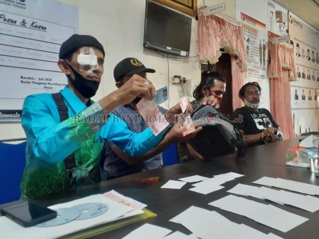 BARBUK: Warga Desa Telang Kecamatan Batang Alai Utara Kabupaten HST menunjukkan bukti sisa amplop yang belum sempat dibagikan kepada warga. | FOTO: JAMALUDDIN/RADAR BANJARMASIN