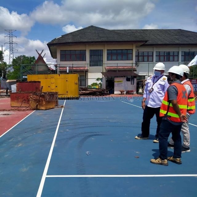 PANTAU PROYEK: Kadispora Kalsel Hermansyah (baju putih) memantau progres renovasi Lapangan Tenis Dharma Praja Banjarmasin, belum lama tadi.