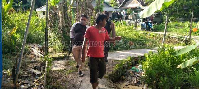 DIBAWA KE MAPOLSEK: Dikawal polisi bersenjata lengkap, Tyson yang masih ngawur dan teler digiring ke mobil patroli. | FOTO: MAULANA/RADAR BANJARMASIN