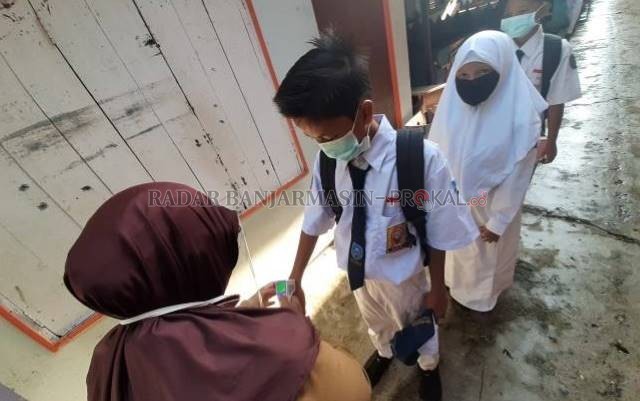 PROTOKOL: Guru mengecek suhu badan siswa SMPN 10 Banjarmasin selama simulasi pembukaan sekolah, November lalu. | FOTO: WAHYU RAMADHAN/RADAR BANJARMASIN