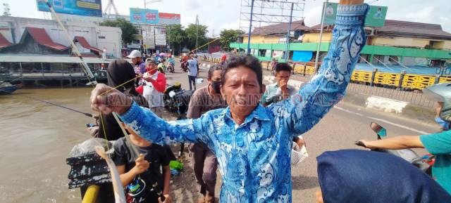 MANCING MANIA: Adnan menunjukkan tangkapan ikan nilanya. Selama banjir melanda Banjarmasin, Jembatan Pangeran Antasari ramai dirubung para mancing mania. | FOTO: ENDANG SYARIFUDDIN/RADAR BANJARMASIN