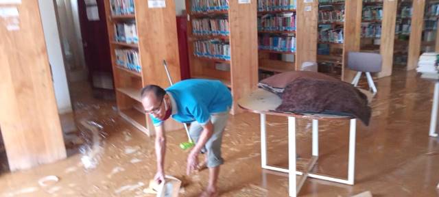 KENA DAMPAK: Petugas membersihkan perpustakaan HST. | FOTO: ISTIMEWA