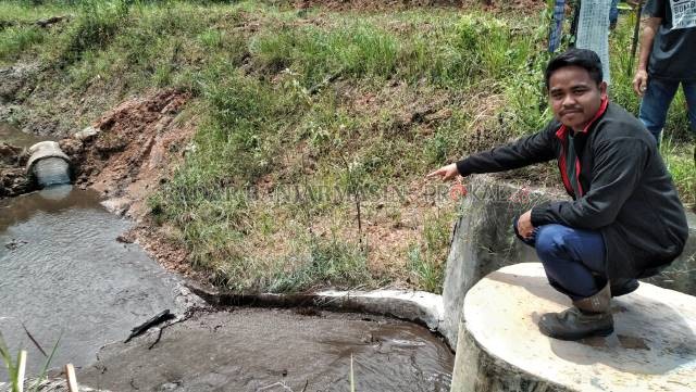 CEMARI SUNGAI: Warga Desa Sebamban Baru menunjukkan air berwarna hitam yang masuk ke anak sungai dari kolam pengolahan limbah perusahaan tambang batu bara di Tanah Bumbu. | FOTO: ZALYAN SHODIQIN ABDI/RADAR BANJARMASIN