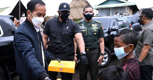 BAGI DONAT: Presiden RI Joko Widodo berbagi makanan kepada anak-anak saat mengunjungi Kabupaten Banjar, salah satu daerah yang terdampak banjir paling besar di Kalsel, kemarin (18/1). | FOTO: SETPERS FOR RADAR BANJARMASIN