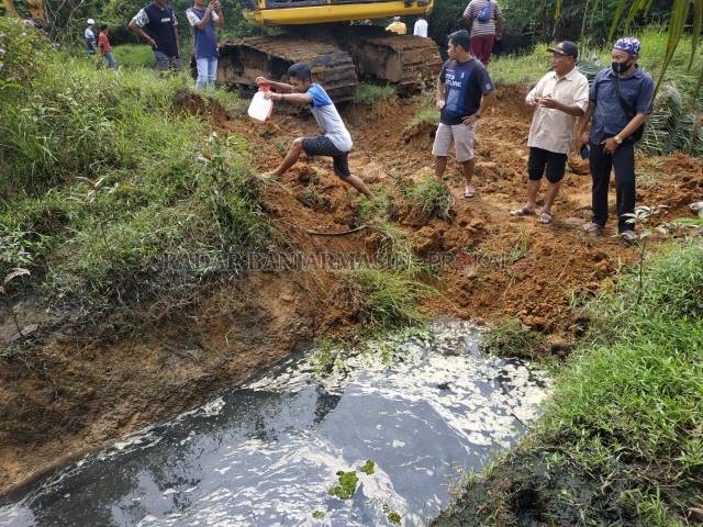 BERBAU: Saluran air limbah pabrik kelapa sawit yang mengarah ke sungai ditutup dengan alat berat, Senin (15/2). Penutupan itu disaksikan warga Desa Jorong dan aparat. | Foto: Norsalim Yahya/Radar Banjarmasin