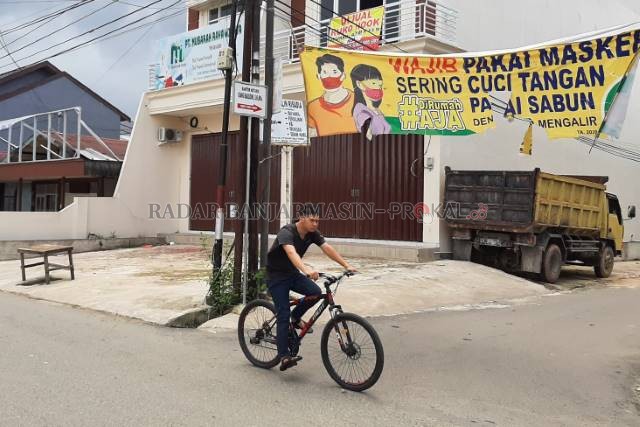 TANPA PEMBATASAN: Tanpa mengenakan masker, warga dengan santai bersepeda di kawasan Pemurus Dalam, kemarin (atas). Kantor Lurah Pemurus Dalam sebagai posko induk PPKM Mikro di kawasan tersebut. | FOTO: WAHYU RAMADHAN/RADAR BANJARMASIN