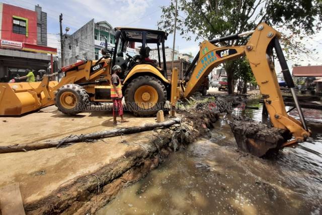 BONGKAR NEGO: Ekskavator mengeruk kawasan Sungai Veteran yang sebagian jembatannya sudah dibongkar kemarin (17/2). Pemko melalui Satgas Normalisasi Sungai masih memerlukan negosiasi sebelum melakukan pembongkaran jembatan bangunan gedung. [FOTO: WAHYU RAM