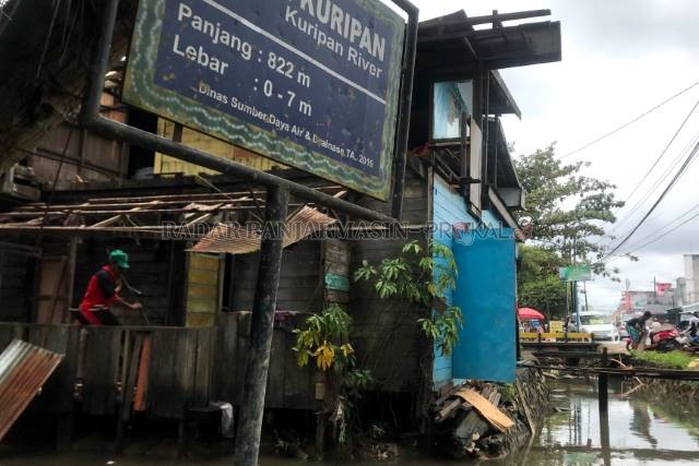 KESADARAN WARGA: Tukang kayu sedang membongkar dapur milik Hj Sainah di Sungai Kuripan, Sabtu (20/2) lalu. | FOTO: WAHYU RAMADHAN/RADAR BANJARMASIN