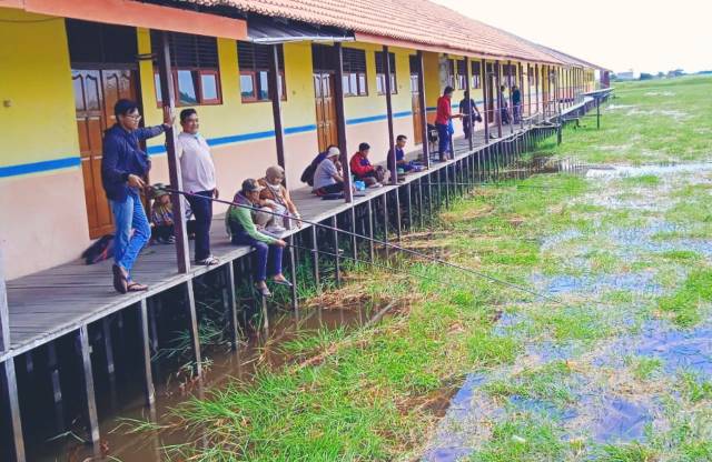 SALURKAN HOBI: Memancing dari teras SMP Sapala, Kecamatan Paminggir. | Foto: Istimewa
