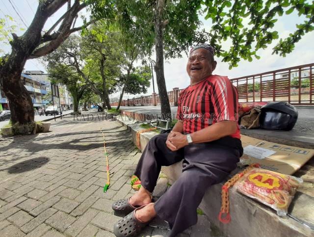 YANG PENTING HALAL: Supiani Akup tertawa lepas bersama karet gelang dagangannya di Siring Ujung Murung. | FOTO: WAHYU RAMADHAN/RADAR BANJARMASIN