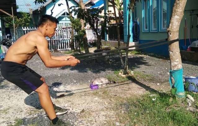 LATIHAN MANDIRI: Pegulat Kalsel M Arbain rajin melatih kekuatan ototnya dengan menarik resistance power rubber band.
