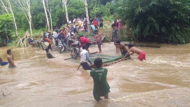 ALTERNATIF: Warga menyeberang menggunakan rakit bambu karena jembatan penghubung Desa Auh dan Kambiyain terputus akibat terjangan air sungai yang begitu deras. | FOTO BPBD BALABGAN FOR RADAR BANJARMASIN.