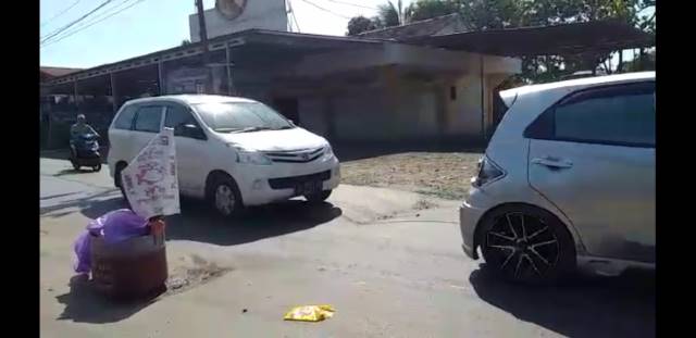 MENGHALANGI JALAN: Tong sampah yang diletakkan warga untuk menghindari kecelakaan bagi pengendara yang melintas karena jalan berlubang.