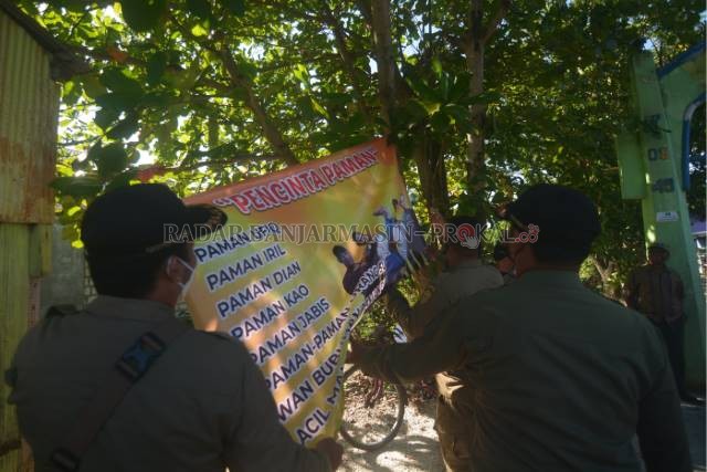 PENCINTA PAMAN: Satpol PP melepas spanduk di Kelurahan Pekauman Kecamatan Banjarmasin Selatan, wilayah PSU Pilgub Kalsel. | FOTO: WAHYU RAMADHAN/RADAR BANJARMASIN